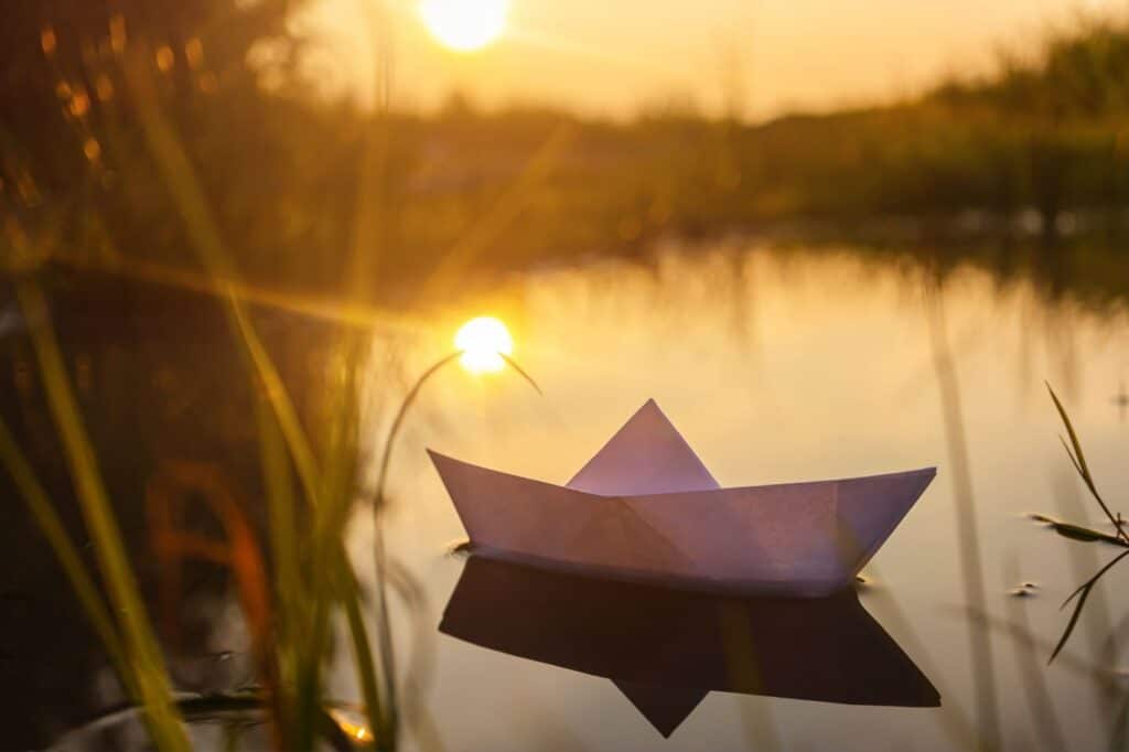 Papirbåd der flyder i solnedgang som symbol på flydende sprog